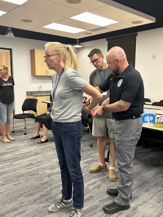 Officer demonstrating handcuffing technique on a student volunteer