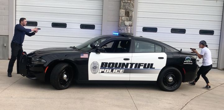 Students running a simulated traffic stop beside a Bountiful Police car