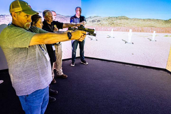 Students aiming training pistols at an interactive simulator screen